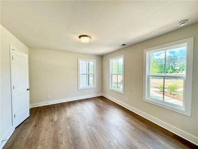 Unfurnished room with dark wood finished floors, baseboards, and a smoke detector