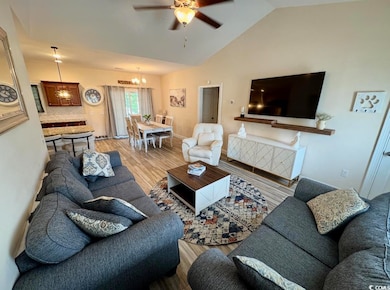 Living area with light wood-style flooring, ceiling fan, a chandelier, and lofted ceiling