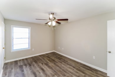 Empty room featuring ceiling fan and dark wood-style flooring