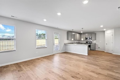 Kitchen featuring gray cabinets, appliances with stainless steel finishes, a peninsula, light countertops, and recessed lighting