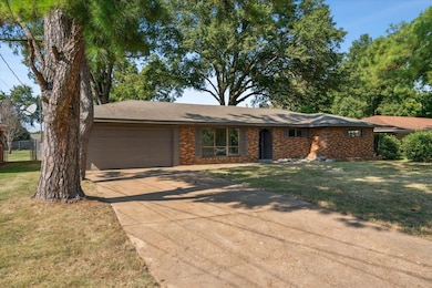 Ranch-style home featuring a front yard and a gara