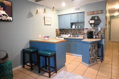 Kitchen with a breakfast bar area, blue cabinetry, light tile patterned floors, light countertops, and tasteful backsplash