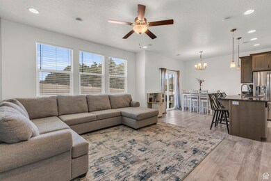 Living room with light wood-type flooring, a ceiling fan, recessed lighting, a textured ceiling, and a chandelier