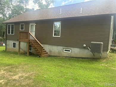 Rear view of property featuring a shingled roof and a yard
