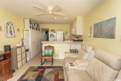 Living area with light tile patterned floors, ceiling fan, crown molding, recessed lighting, and stacked washer / dryer