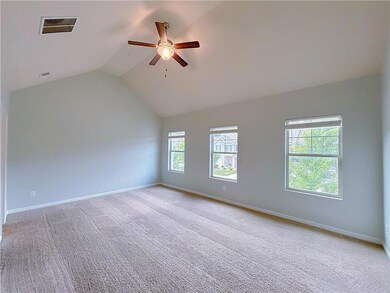 Empty room featuring a ceiling fan, lofted ceiling, light colored carpet, and baseboards