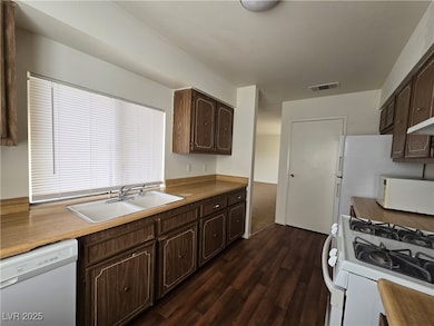 Kitchen featuring white appliances, dark wood-style floors, and dark brown cabinetry