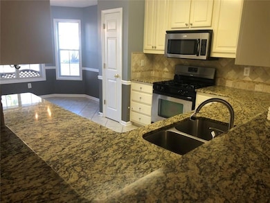 Kitchen with dark stone counters, a sink, stainles