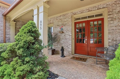 View of exterior entry featuring french doors, brick siding, and covered porch