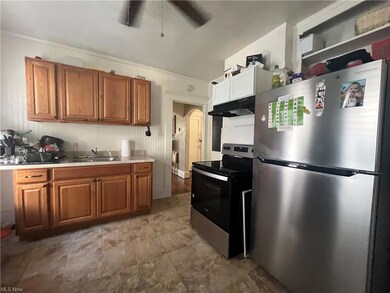 Kitchen with dark tile floors, crown molding, brown cabinets, and stainless steel appliances