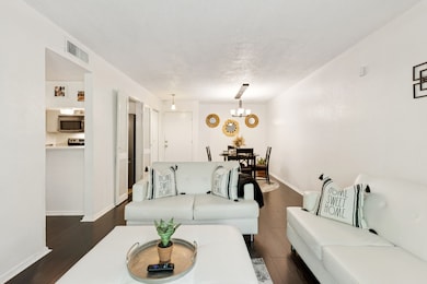Living area featuring dark wood-type flooring, a textured ceiling, and a chandelier
