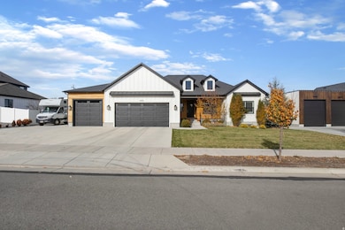 Modern farmhouse featuring concrete driveway, an attached garage, a front yard, and board and batten siding
