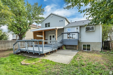 Rear view of property featuring a fenced backyard, a deck, and a shingled roof
