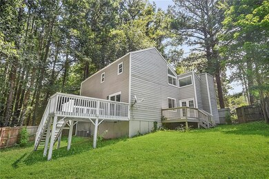 Back of property with stairs, a wooden deck, view of wooded area, and a chimney
