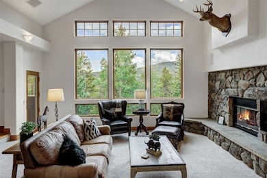 Living room featuring carpet, a fireplace, and high vaulted ceiling
