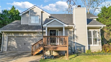 View of front facade featuring roof with shingles, concrete driveway, a chimney, and an attached garage