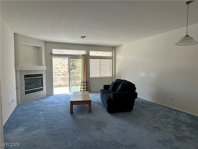 Living area featuring visible vents, a textured ceiling, carpet flooring, and a tiled fireplace