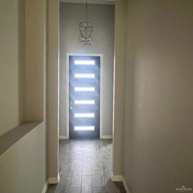 Entryway with wood finished floors, a chandelier, and baseboards