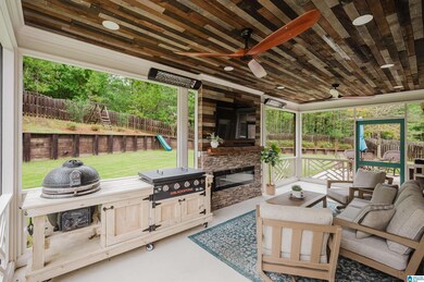 Step outside to the showstopper — a covered and screened patio with beautiful custom woodwork on the ceiling, a cozy electric fireplace, an area for a mounted TV, and two upper-mounted electric heaters, all operated by switch.