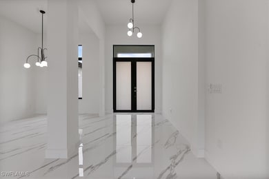 Foyer with a chandelier, marble tiled floors, and