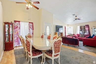 Dining area with ceiling fan, light wood-style flooring, and high vaulted ceiling