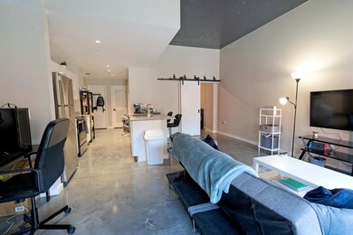 Living room featuring a barn door, concrete flooring, baseboards, and recessed lighting