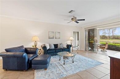Tiled living room with ceiling fan and crown moldi
