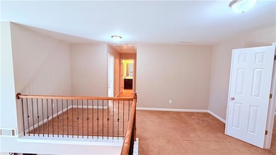 Hall featuring attic access and light colored carpet