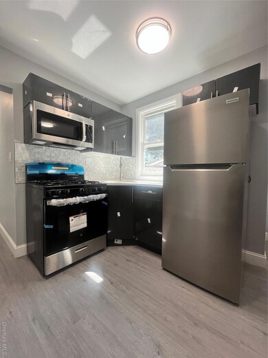 Kitchen with fridge, stainless steel range oven, tasteful backsplash, light wood-style floors, and light countertops