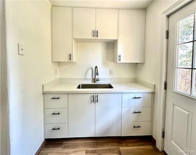 Kitchen with white cabinets, light stone counters, and wood finished floors