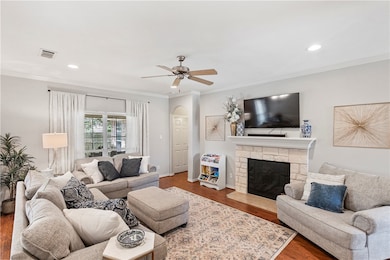 Living area with a ceiling fan, crown molding, woo