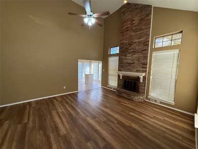 Unfurnished living room with a fireplace, dark wood-style flooring, a ceiling fan, and high vaulted ceiling