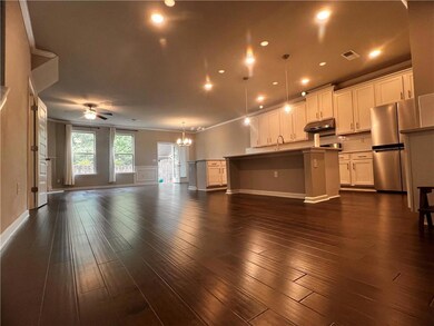 Unfurnished living room with a chandelier, ceiling fan, a sink, dark wood finished floors, and baseboards
