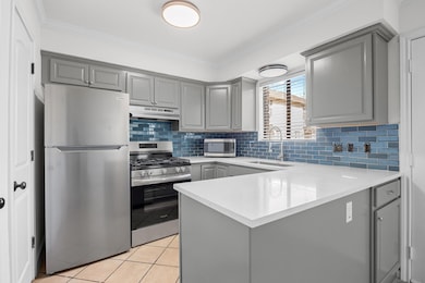 Kitchen with gray cabinets, appliances with stain
