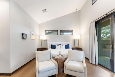 Bedroom with access to exterior, wood finished floors, high vaulted ceiling, and baseboards