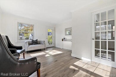 Sitting room with ornamental molding and light wood-style floors