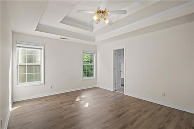 Unfurnished room featuring a raised ceiling, crown molding, dark wood-type flooring, and ceiling fan