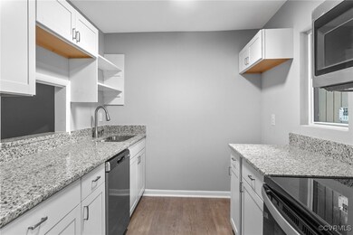 Kitchen with dark wood-type flooring, light stone