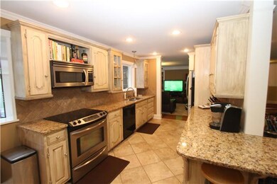 GRANITE KITCHEN WITH GLAZED CABINETS AND STAINLESS STEEL APPLIANCES 