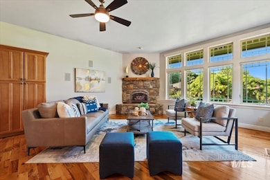 Living room featuring a stone fireplace, ceiling fan, and light wood-type flooring