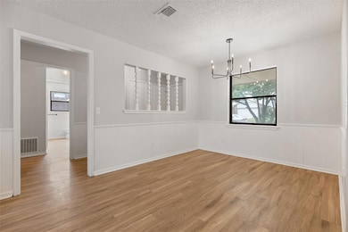 Empty room with a wainscoted wall, a chandelier, w