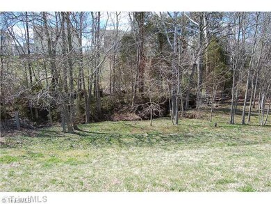 Exterior Back. Wooded area behind the home, property line ends in the middle of the creek.