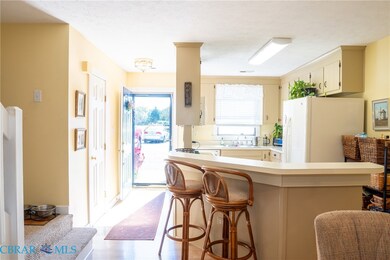 Kitchen with light countertops, cream cabinets, freestanding refrigerator, a kitchen bar, and a textured ceiling