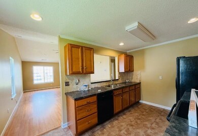 Kitchen featuring backsplash, brown cabinets, black appliances, recessed lighting, and a textured ceiling