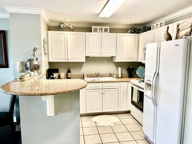 Kitchen with white appliances, a peninsula, a sink, white cabinets, and ornamental molding