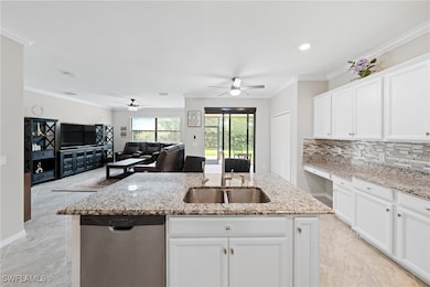 Kitchen featuring crown molding, white cabinetry, stainless steel dishwasher, an island with sink, and decorative backsplash