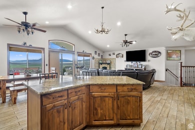 Kitchen featuring ceiling fan, light wood finished floors, a fireplace, light stone countertops, and a kitchen island