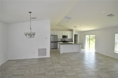 Kitchen with open floor plan, white cabinets, appliances with stainless steel finishes, vaulted ceiling, and a chandelier