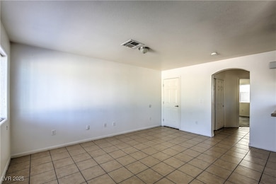 Spare room featuring arched walkways, light tile p