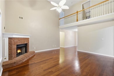 Unfurnished living room with a high ceiling, dark wood finished floors, a brick fireplace, and a ceiling fan